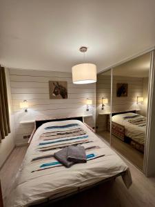 une chambre avec un grand lit avec un miroir dans l'établissement Appart entre lac et montagne, à Saint-Jean-de-Sixt