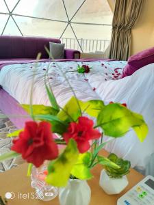 a bed with flowers in vases on a table at wadi rum caeser camp in Wadi Rum