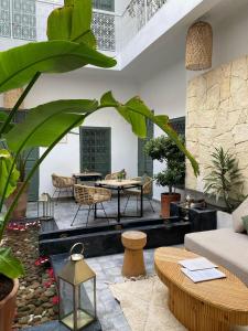 una sala de estar con mesas, sillas y plantas. en Riad Villa Wengé & Spa en Marrakech