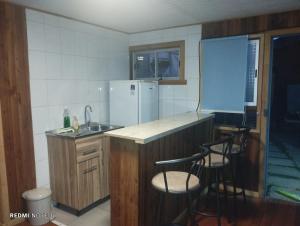 uma cozinha com um balcão, um frigorífico e 2 bancos em Cabañas Janico em Loncoche