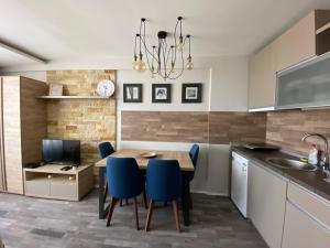 a kitchen and dining room with a table and blue chairs at Milmari Premier 28 Kopaonik in Kopaonik