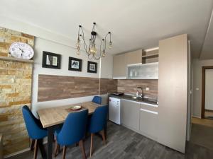 a kitchen with a wooden table and blue chairs at Milmari Premier 28 Kopaonik in Kopaonik +17 photos