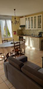 een woonkamer met een bank en een tafel en een keuken bij Gîte Le Fruitier Beaugency in Beaugency