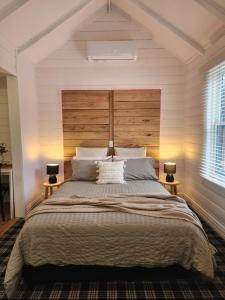 a bedroom with a large bed with a wooden headboard at Daylesford - Frog Hollow Estate -THE COTTAGE - enjoy a relaxing and romantic night away in our gorgeous little one Bedroom ROMANTIC COTTAGE under the apple tree with water views in Daylesford
