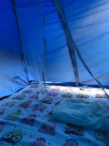 a bed in a tent with a blanket on it at Camping beira mar in Bertioga