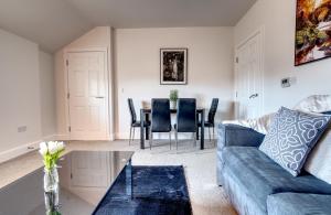 ein Wohnzimmer mit einem Sofa und einem Tisch in der Unterkunft #St Georges Court by DerBnB, Spacious 2 Bedroom Apartments, Free Parking, WI-FI, Netflix & Within Walking Distance Of The City Centre in Derby