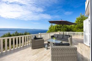 une terrasse avec une table, des chaises et un parasol dans l'établissement Villa Lea with a beautiful view and swimming pool, à Stanići