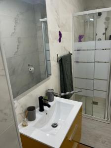 La salle de bains blanche est pourvue d'un lavabo et d'une douche. dans l'établissement Apartamento completo, mascotas aceptadas, à Arenales del Sol