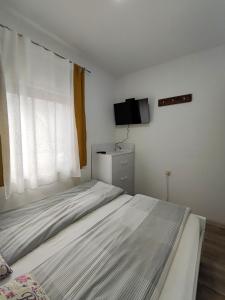 una camera bianca con letto e televisore di Apartment Natalija a Kopaonik