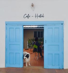 un perro parado frente a un garaje azul en Flor de León Café - Hostal, en Barichara