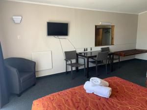 une chambre d'hôtel avec un lit, une table et une télévision dans l'établissement Apple Motor Inn, à Hastings