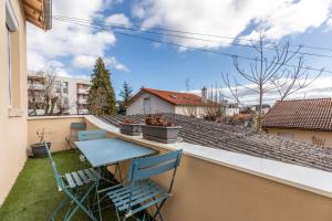 een balkon met een tafel en stoelen op een dak bij La maison de Vallières in Clermont-Ferrand