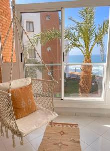 a swing in a room with a palm tree and a window at Dar Mustapha in Sidi Ifni
