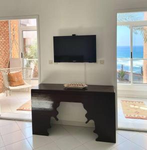 a living room with a table with a tv on the wall at Dar Mustapha in Sidi Ifni