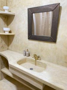 a bathroom with a sink and a mirror and shelves at Dar Mustapha in Sidi Ifni