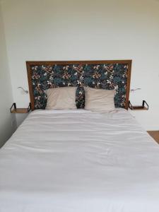 een slaapkamer met een groot bed met witte lakens en kussens bij La Vaillante in Saint-Valery-sur-Somme