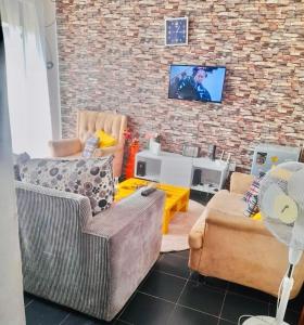 una sala de estar con 2 sofás y una pared de ladrillo en Beautiful and Affordable 1brm in Milimani en Kisumu