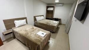 a hotel room with two beds and a flat screen tv at Boa Esperança Apart Hotel in Boa Esperança