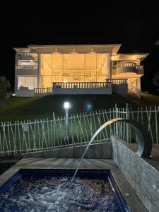 a home at night with a fountain in front of a house at Lujosa Finca El Ensueño Cerritos Pereira in Pereira