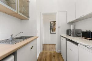 uma cozinha branca com um lavatório e um micro-ondas em Cosy place near Camden town em Londres