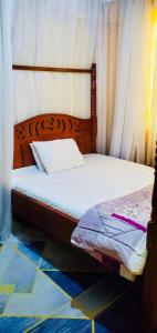 a bed with a wooden headboard and white sheets at Beautiful and Affordable 1brm in Milimani in Kisumu