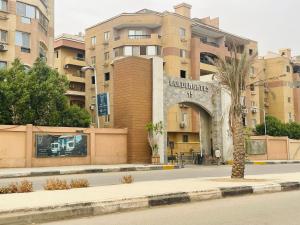 a building with a palm tree in front of a street at Mokattem private Condo in Cairo