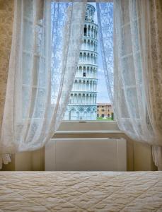 een slaapkamer met een raam met uitzicht op de scheve toren van pisa bij Residenza d'Epoca Relais I Miracoli in Pisa