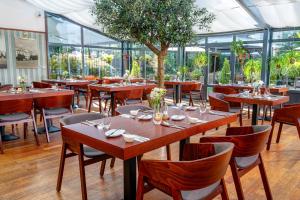 ein Restaurant mit Tischen, Stühlen und einem Baum in der Unterkunft Hotel Golden Eagle in Levice