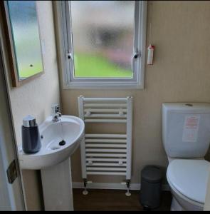 a bathroom with a sink and a toilet and a window at Port Carlisle Caravan near Bowness on Solway in Carlisle