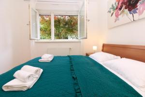 a bedroom with a green bed with towels on it at Galerija in Strmec Samoborski