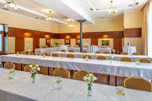 Großes Zimmer mit Tischen, Stühlen und weißer Bettwäsche. in der Unterkunft Hotel Golden Eagle in Levice