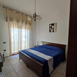 Un dormitorio con una cama azul y una ventana en B&B La Rosa Dei Venti Sardinya, en Sinnai