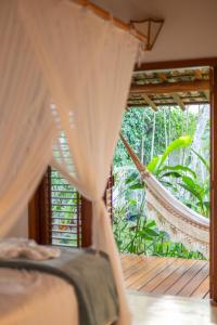 a bed and a hammock in a room with a window at Paraíso Casa Branca in Arraial d'Ajuda