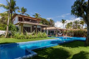 a villa with a swimming pool in front of a house at Paraíso Casa Branca in Arraial d'Ajuda