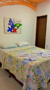 a bed in a bedroom with a painting on the wall at Pousada Villa Mariposa in Beberibe