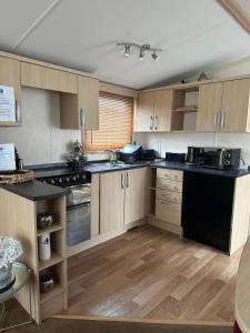 a kitchen with wooden cabinets and black counter tops at BRENDA in Meliden