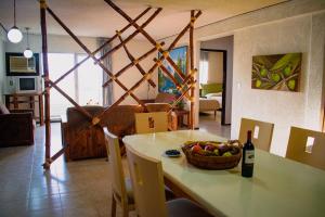a table with a bowl of fruit and a bottle of wine at Suites del Sol Hotel & Apartments in Mérida