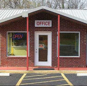 um edifício de tijolos vermelhos com um letreiro de escritório em Regency Inn em Forrest City
