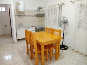 cocina con mesa de madera, sillas y ventilador en Alojamiento Laureant - Capitán Sarmiento - Buenos Aires in 