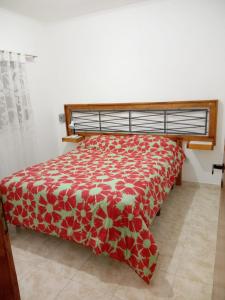 1 dormitorio con 1 cama con colcha roja y blanca en Alojamiento Laureant - Capitán Sarmiento - Buenos Aires in 