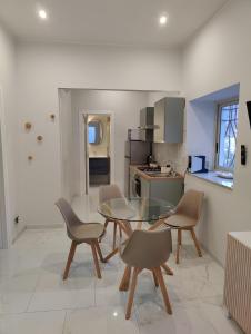 una cucina con tavolo in vetro e sedie di Cuttigghiu Holiday Apartment a Catania