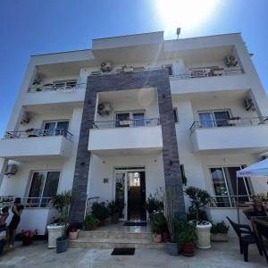 a large white building with people sitting outside of it at Apartments kupi ul rudaj 41 in Ulcinj