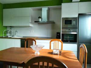 een keuken met een houten tafel met stoelen en apparatuur bij Casa Mallou in San Mamede de Carnota +12 foto's