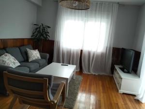 een woonkamer met een bank en een tv bij Casa Mallou in San Mamede de Carnota