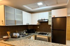 uma cozinha com armários brancos e um frigorífico preto em Studio cozy totalement refait avec toutes les commodités necessairessitué au parc de Mohammedia em Mohammedia