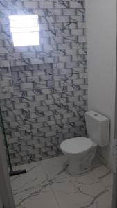 a bathroom with a white toilet and a window at Residencial Praia Quente casas in Nova Viçosa