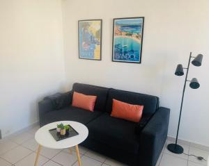 a living room with a black couch and a table at Studio climatisé hypercentre Bandol et Plages in Bandol +7 photos