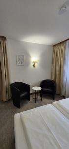 ein Hotelzimmer mit 2 Betten, einem Tisch und Stühlen in der Unterkunft Hotel Garni Vierjahreszeiten in Bad Staffelstein