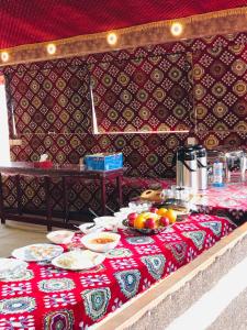a table with plates of food on a red table cloth at Wadi rum Golden land camp in Wadi Rum