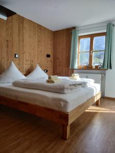 1 dormitorio con 1 cama grande con sábanas blancas y ventana en Ferienwohnung Alpenidylle - Chiemgau Karte, en Inzell